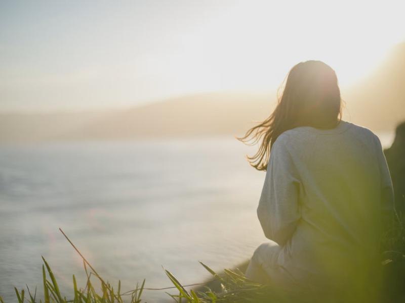 A woman standing by the sea at sunset